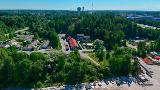 Ilmakuvassa Käärmekallion alue, jossa tie ja sen ympärillä rakennuksia ja puustoa.