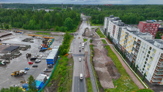 Katu, jossa kulkee jalankulun ja pyörätien lisäksi ajoneuvoliikennettä ja sitä reunustaa läheinen asuinalue ja työmaa koppeineen.