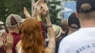 Punatukkainen nainen taputtaa konsertissa tatuoidut kädet ylhäällä. 