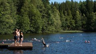 Ihmisiä uimassa ja laiturilla.