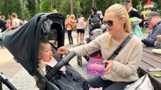 Äiti Saara ja 1-vuotias Iris ruokailemassa puistoruokailussa. Aurinko paistaa.