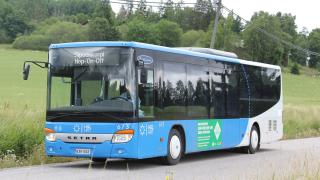 Hop-On Hop-Off-bussi ajaa tiellä pellon keskellä.