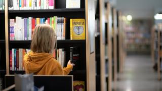 The student is shelving books in the library.