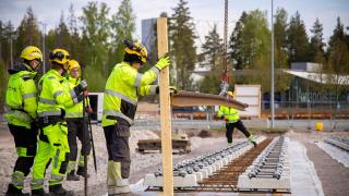 Rakentajat ohjaavat ratakiskoa paikoilleen. 