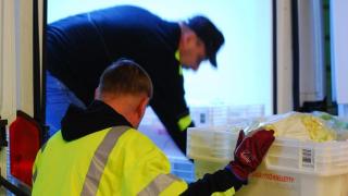 Kuljettajat lastaavat ruokalaatikoita pakettiautoon.