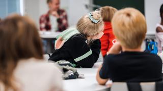 Oppilaat istuvat luokassa ja kuuntelevat opettajaa.
