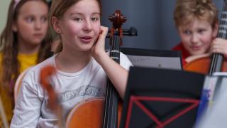 Tempo-orkesterin lapsia soittamassa nojaamassa selloihinsa.